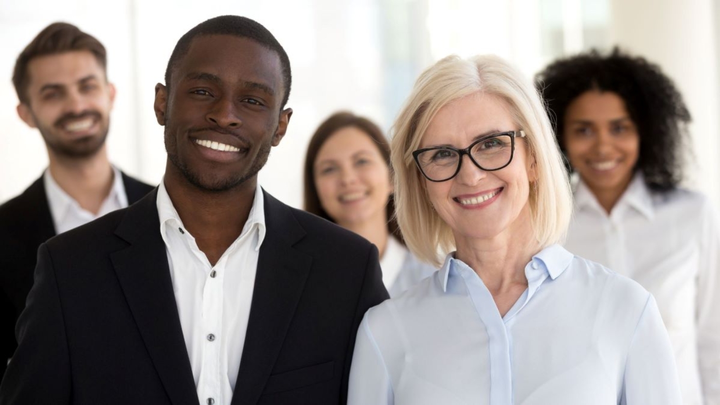 Multigenerational team of professionals standing together in an office, reflecting diversity and teamwork.