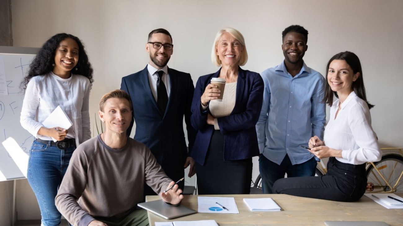 Multigenerational team of professionals standing together in an office, reflecting diversity and teamwork